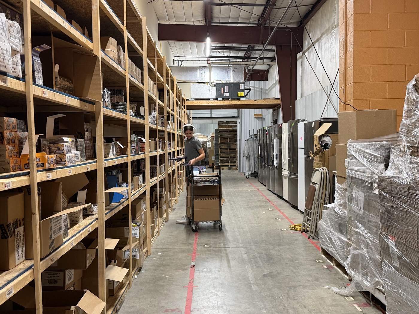 A StreetRobin team member picking and fulfilling orders from organized warehouse shelving.